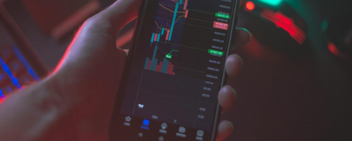 Hand holding smartphone displaying cryptocurrency trading app with financial data.