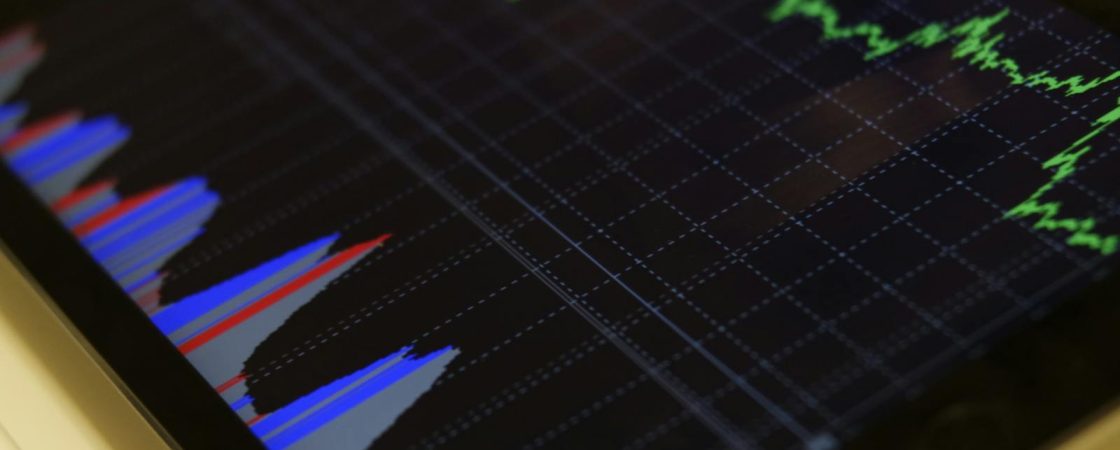 Close-up of a tablet displaying stock market analysis with colorful graphs.