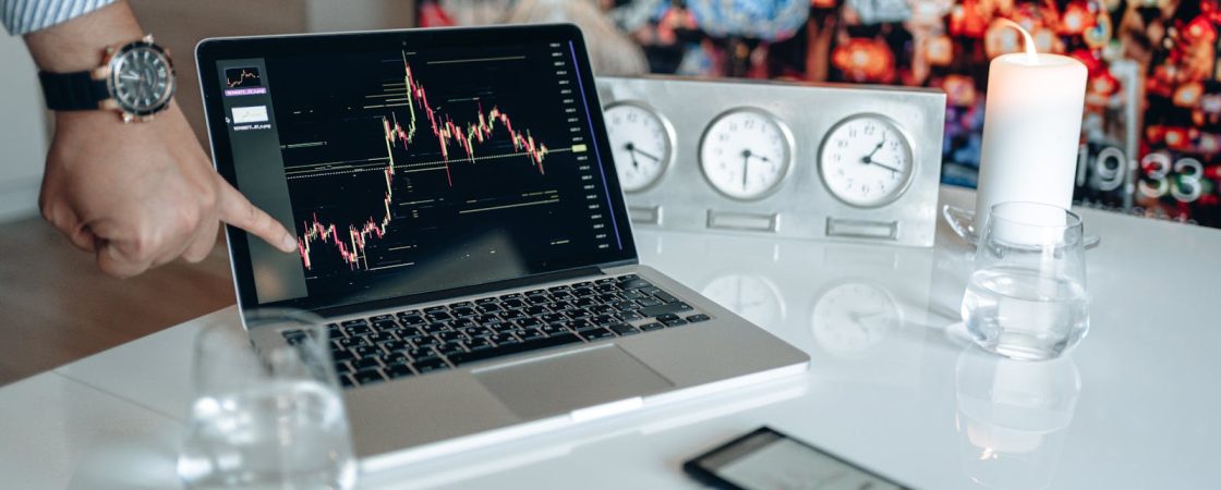 Businessman pointing at a financial graph on a laptop screen, showcasing stock market analysis.