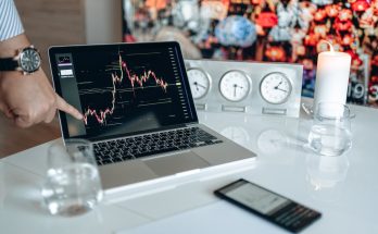 Businessman pointing at a financial graph on a laptop screen, showcasing stock market analysis.