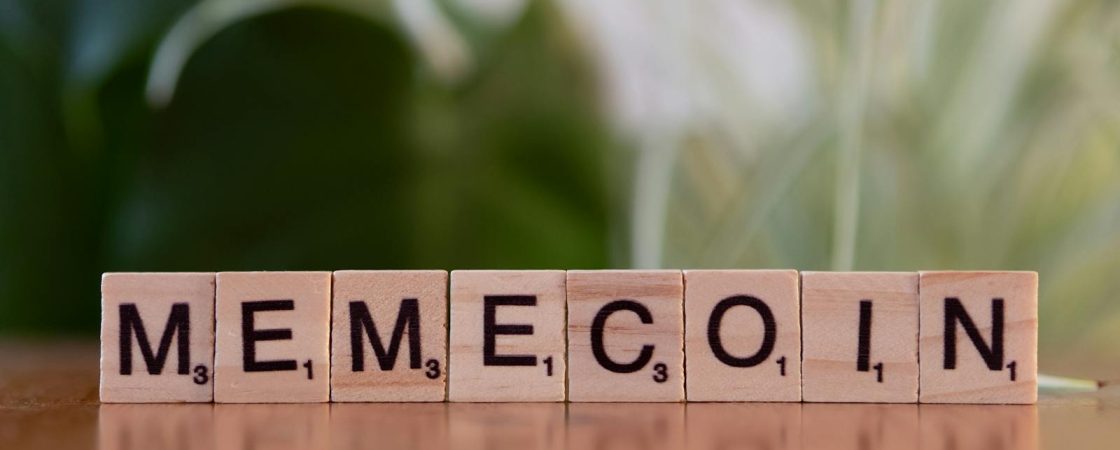 Wooden tiles spelling 'Memecoin' on a blurred background.