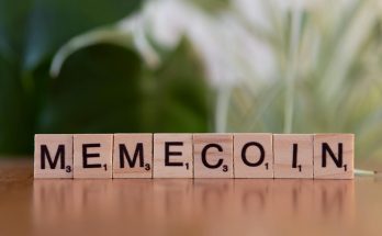 Wooden tiles spelling 'Memecoin' on a blurred background.